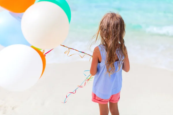 Rückansicht eines kleinen Mädchens mit Luftballons am Strand — Stockfoto