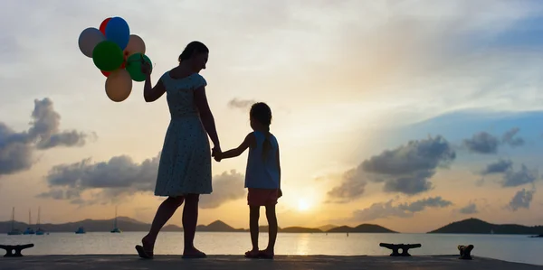 Gelukkige familie met ballonnen bij zonsondergang — Stockfoto