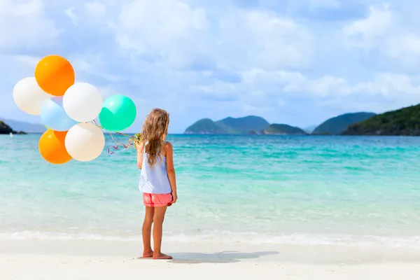 Back view of little girl with balloons at beach — Stock Photo, Image
