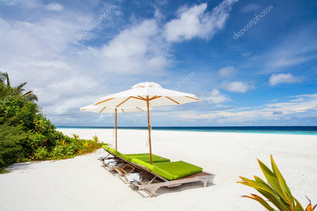 Wooden lounge chairs on a beautiful tropical beach at Maldives