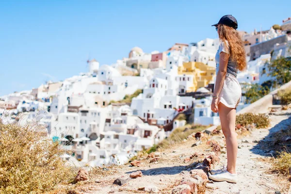 ギリシャのサントリーニ島に伝統的な白い建築でOia村の息をのむような景色を楽しんでかわいい前10代の女の子 — ストック写真