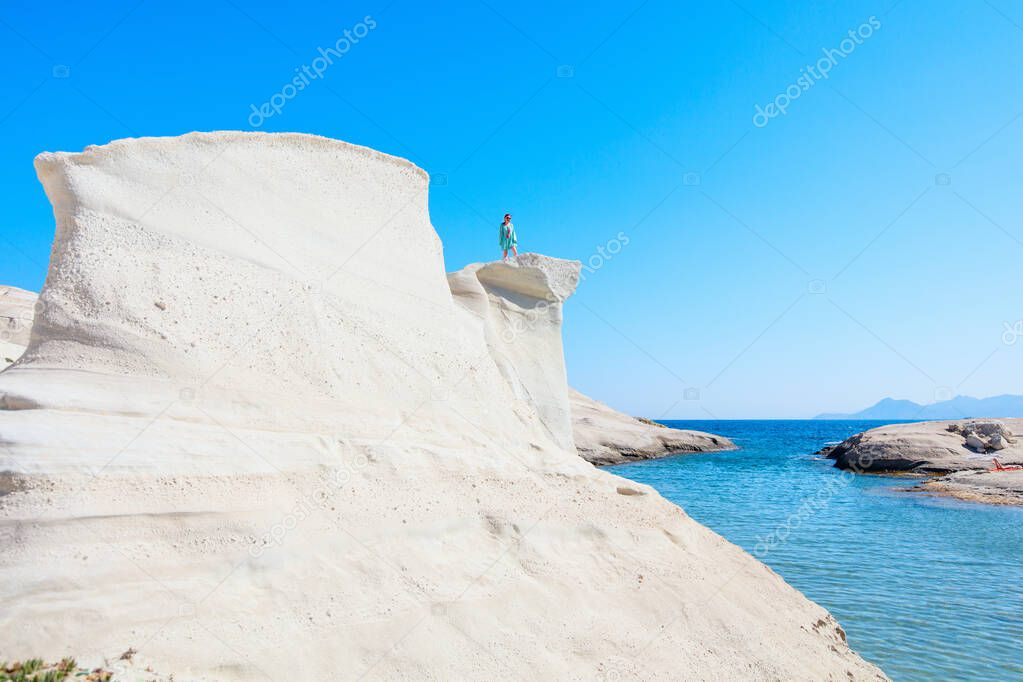 Attractive young woman walking on the lunar like landscape of Sarakiniko volcanic rock formations on island of Milos in Greece