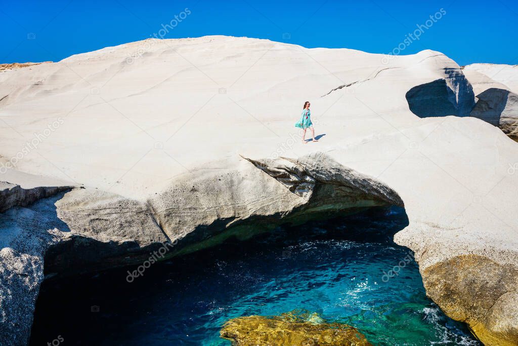 Attractive young woman walking on the lunar like landscape of Sarakiniko volcanic rock formations on island of Milos in Greece