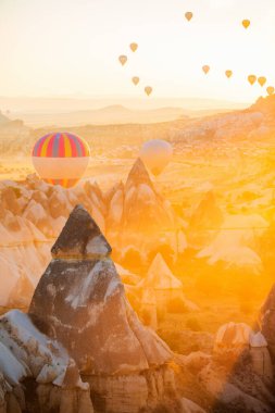 Gorgeous sunrise scenery of hot air balloons flying over Love valley with rock formations and fairy chimneys in Cappadocia Turkey