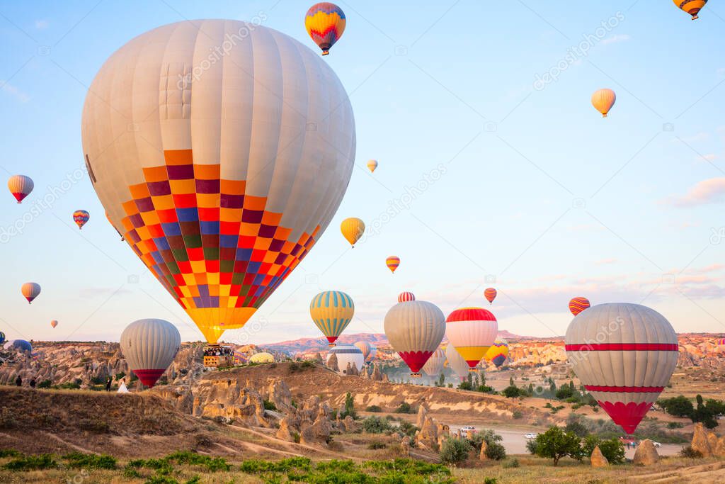 Scenery of hot air balloons flying over valley with rock formations and fairy chimneys in Cappadocia Turkey