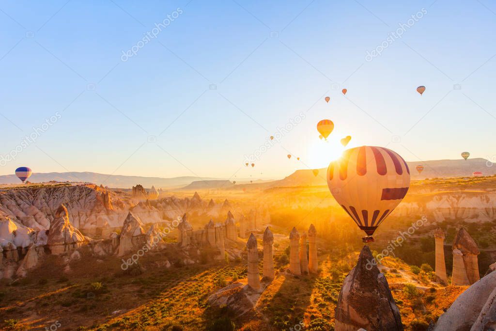 Gorgeous sunrise scenery of hot air balloons flying over Love valley with rock formations and fairy chimneys in Cappadocia Turkey