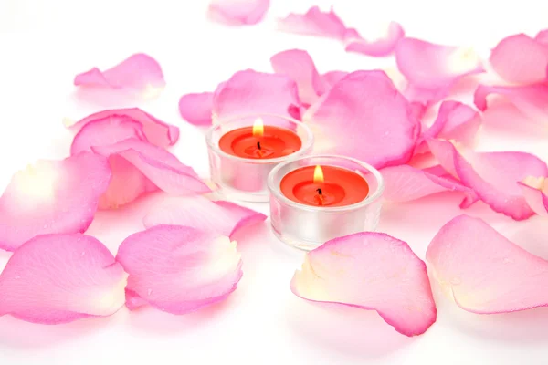 Pétales d'une rose rose et bougies allumées — Photo