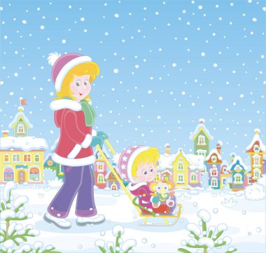 Genç ve sevimli anne, karlı bir kış gününde, küçük bir kasabanın karla kaplı bir caddesinde komik bir oyuncak fille mutlu küçük kızını kızaklıyor.