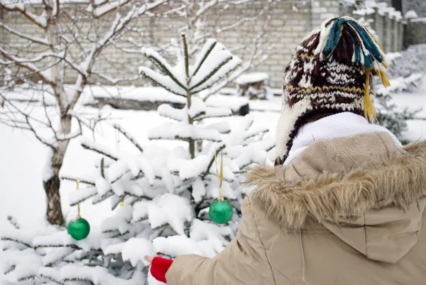A teen girl decorating Christmas tree outdoors — Stock Photo, Image