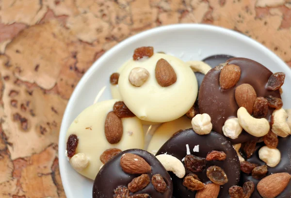 Black, white and milk chocolate with nuts and raisins — Stock Photo, Image