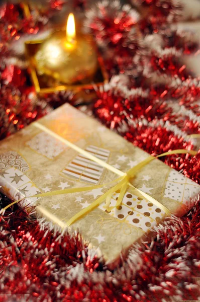 Christmas present and a lit candle on the red background — Stock Photo, Image