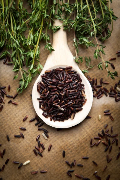 Red rice on wooden spoon — Stock Photo, Image