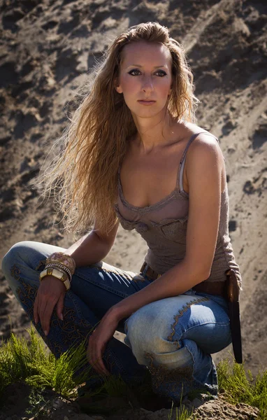 Cowgirl in jeans su uno sfondo sabbioso — Foto Stock