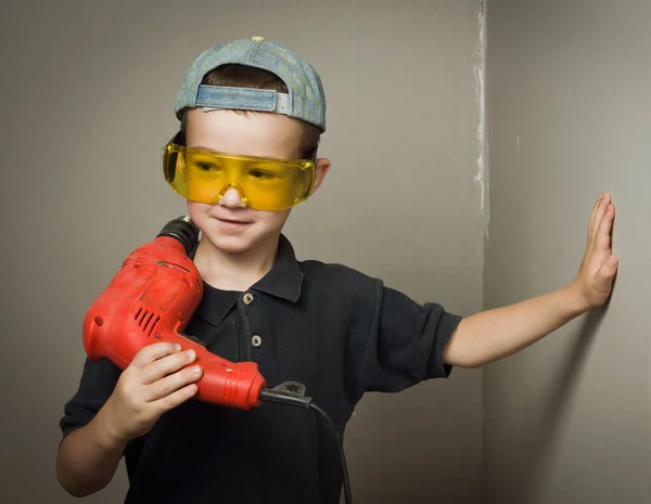 Junge in Schutzbrille mit Bohrmaschine — Stockfoto