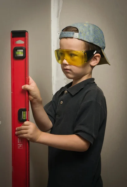 Niño en gafas con un nivel de pared — Foto de Stock