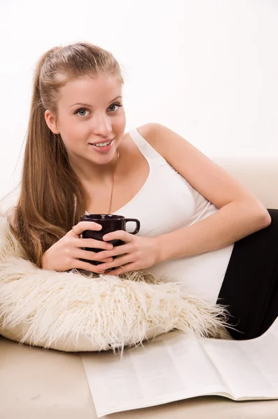 Attractive woman with a coffee cup lying on a sofa — Stock Photo, Image