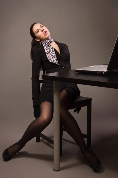 Mulher em um terno preto sentado em uma mesa de escritório — Fotografia de Stock