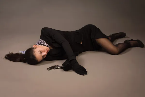 Woman in a black suit with gun lying on the floor — Stock Photo, Image