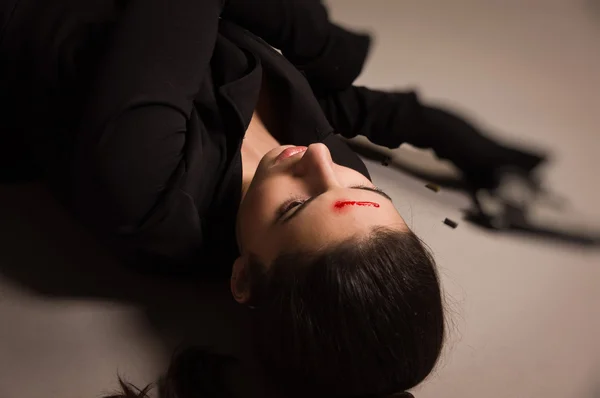 Mujer en traje negro con pistola tirada en el suelo — Foto de Stock