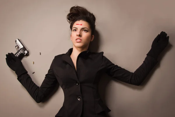 Woman in a black suit with gun lying on the floor — Stock Photo, Image