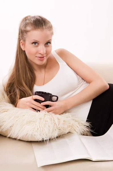 Attractive woman with a coffee cup lying on a sofa — Stock Photo, Image