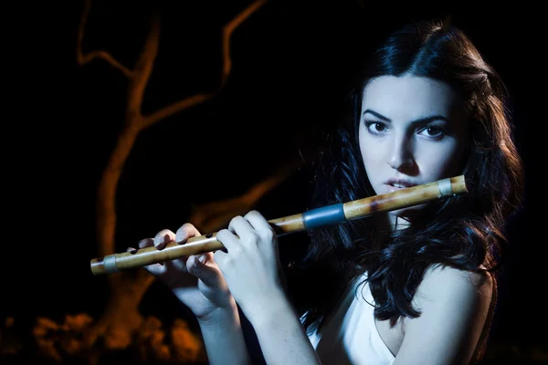 Sensualidade morena toca uma flauta de madeira — Fotografia de Stock