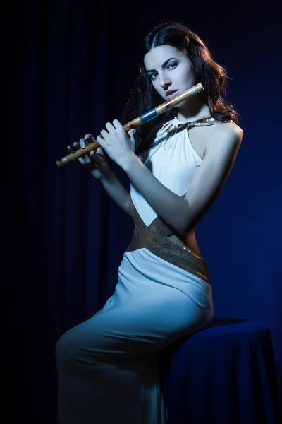 Sensuality brunette plays a wooden flute — Stock Photo, Image