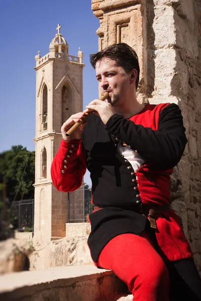 Man in a medieval suit plays a flute — Stock Photo, Image