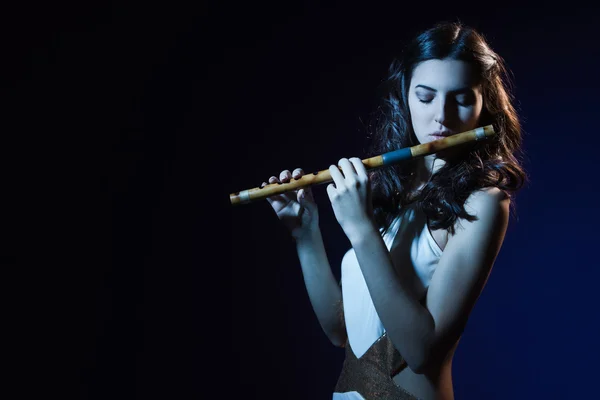 Брюнетка чувственности играет на деревянной флейте — стоковое фото