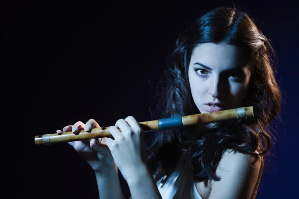 Sensuality brunette plays a wooden flute — Stock Photo, Image