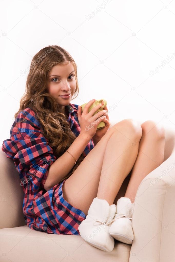 Attractive woman with a tea cup sitting on a armchair