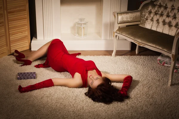 Модная дама в красном платье, лежащая на полу — стоковое фото