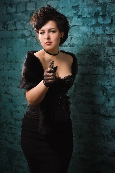 Fashionable women in a black shoots a gun — Stock Photo, Image