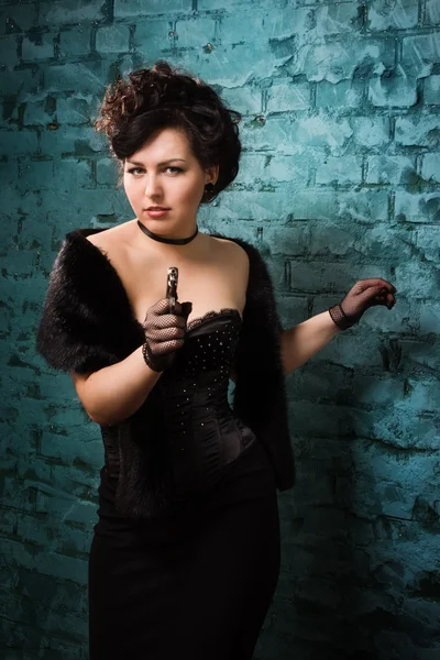 Fashionable women in a black shoots a gun — Stock Photo, Image