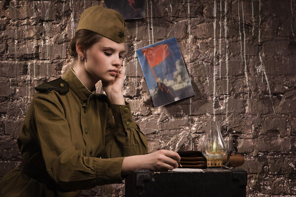 Soviet female soldier in uniform of World War II writes a letter