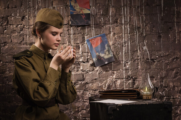 Soviet female soldier in uniform of WWII in the dugout