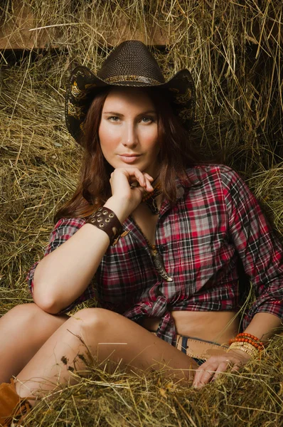 Cowgirl zittend op hooi in de stal — Stockfoto