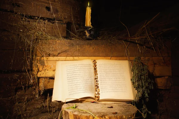 Oud boek en kaars in een donker interieur — Stockfoto