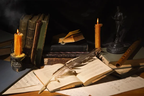 Oude boeken en kaarsen op houten tafel — Stockfoto