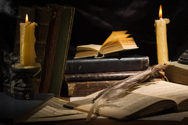 Oude boeken en kaarsen op houten tafel — Stockfoto