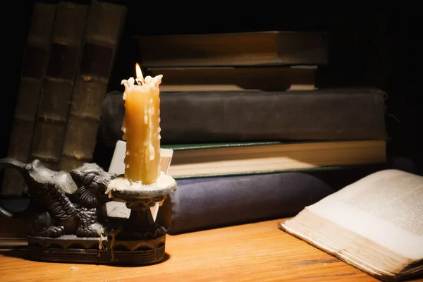 Vecchi libri e candele su tavolo di legno — Foto Stock