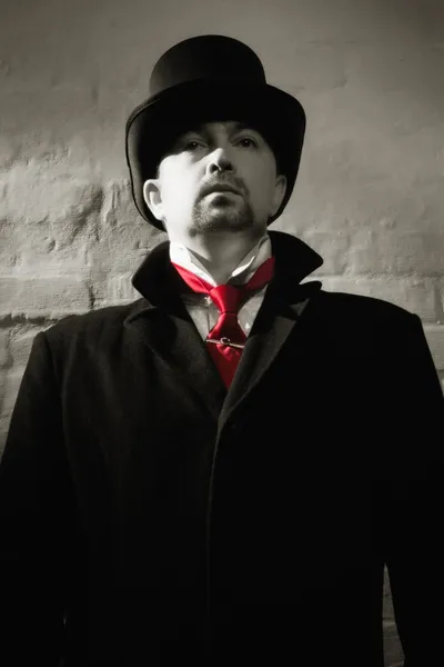 Uomo in cappotto nero, cilindro e cravatta rossa — Foto Stock