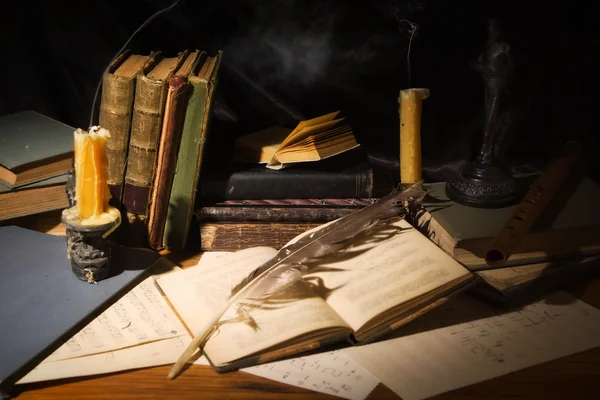 Oude boeken en kaarsen op houten tafel — Stockfoto