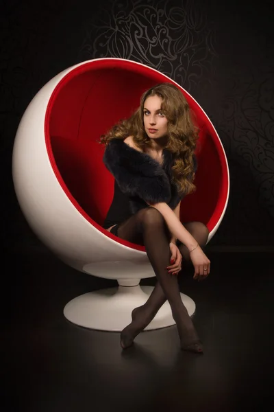 Sexual woman sitting in a red ball-chair — Stock Photo, Image