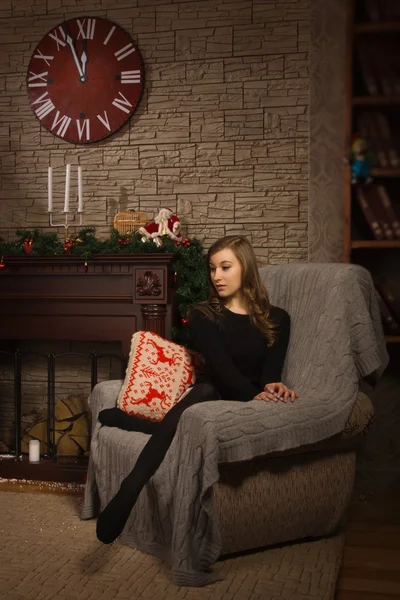 Chica joven sentada junto a la chimenea — Foto de Stock