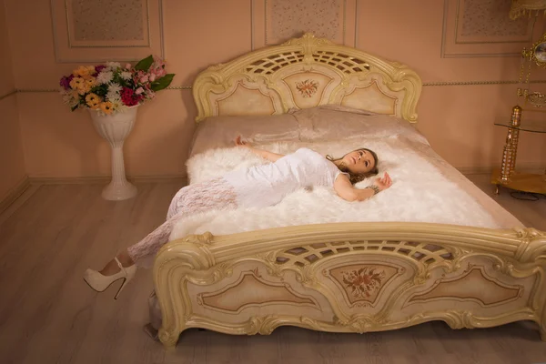 Молодая элегантная девушка лежит на кровати — стоковое фото