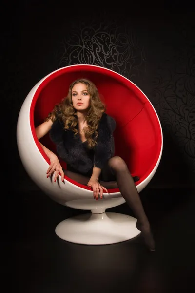 Sexual woman sitting in a red ball-chair — Stock Photo, Image