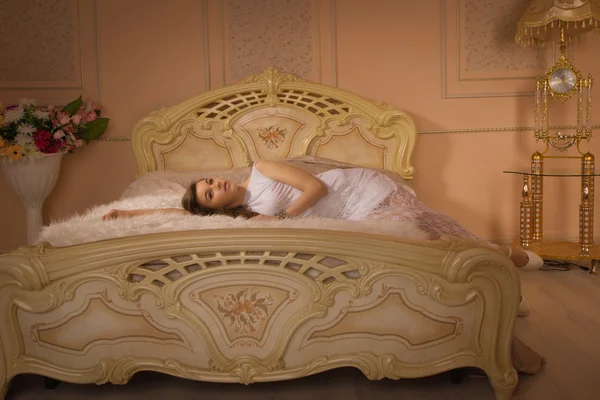 Молодая элегантная девушка лежит на кровати — стоковое фото