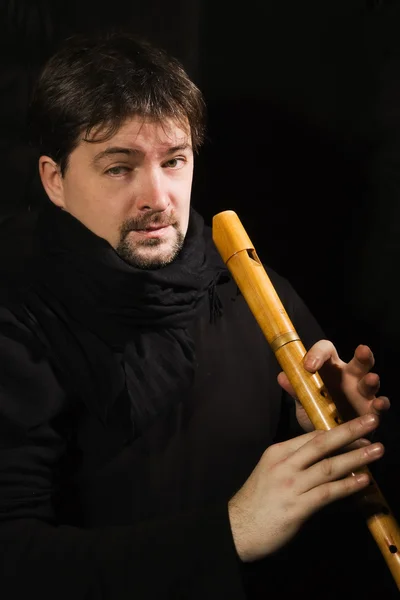 Man in black plays a flute — Stock Photo, Image