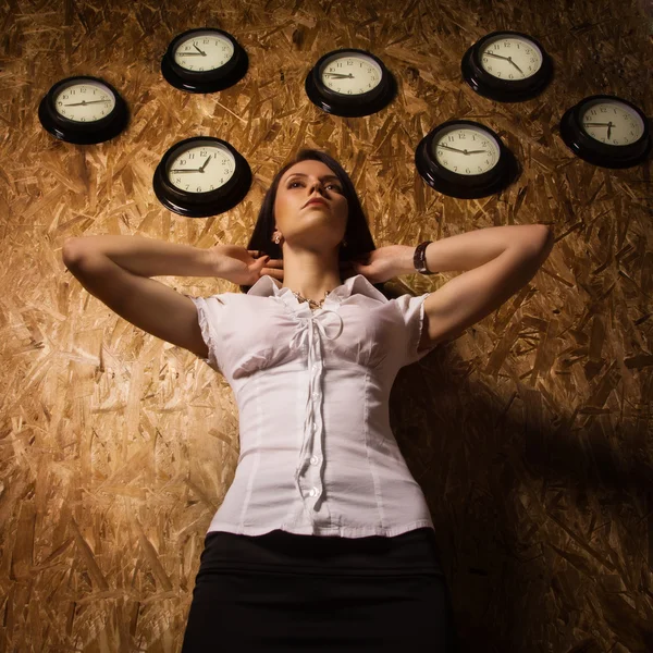 Büromädchen auf dem Hintergrund einer Wanduhr — Stockfoto